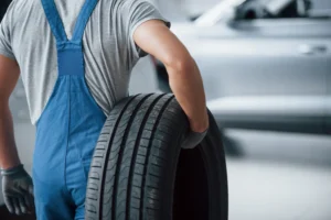 used tyres singapore, A tyre specialist carrying a used tyres singapore for a silver car